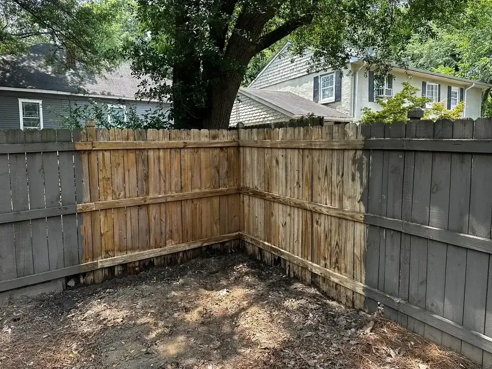 The same fence corner with the failed section rebuilt in new pressure-treated pickets