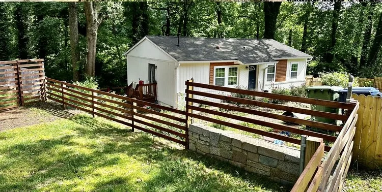 A horizontal stained-cedar fence and gate built along a stone retaining wall behind a home in east metro Atlanta